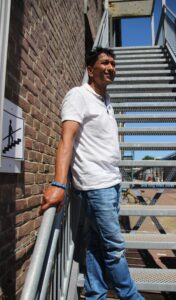 Reza Karamat Ali staat buiten op een stalen trap en kijkt in de verte